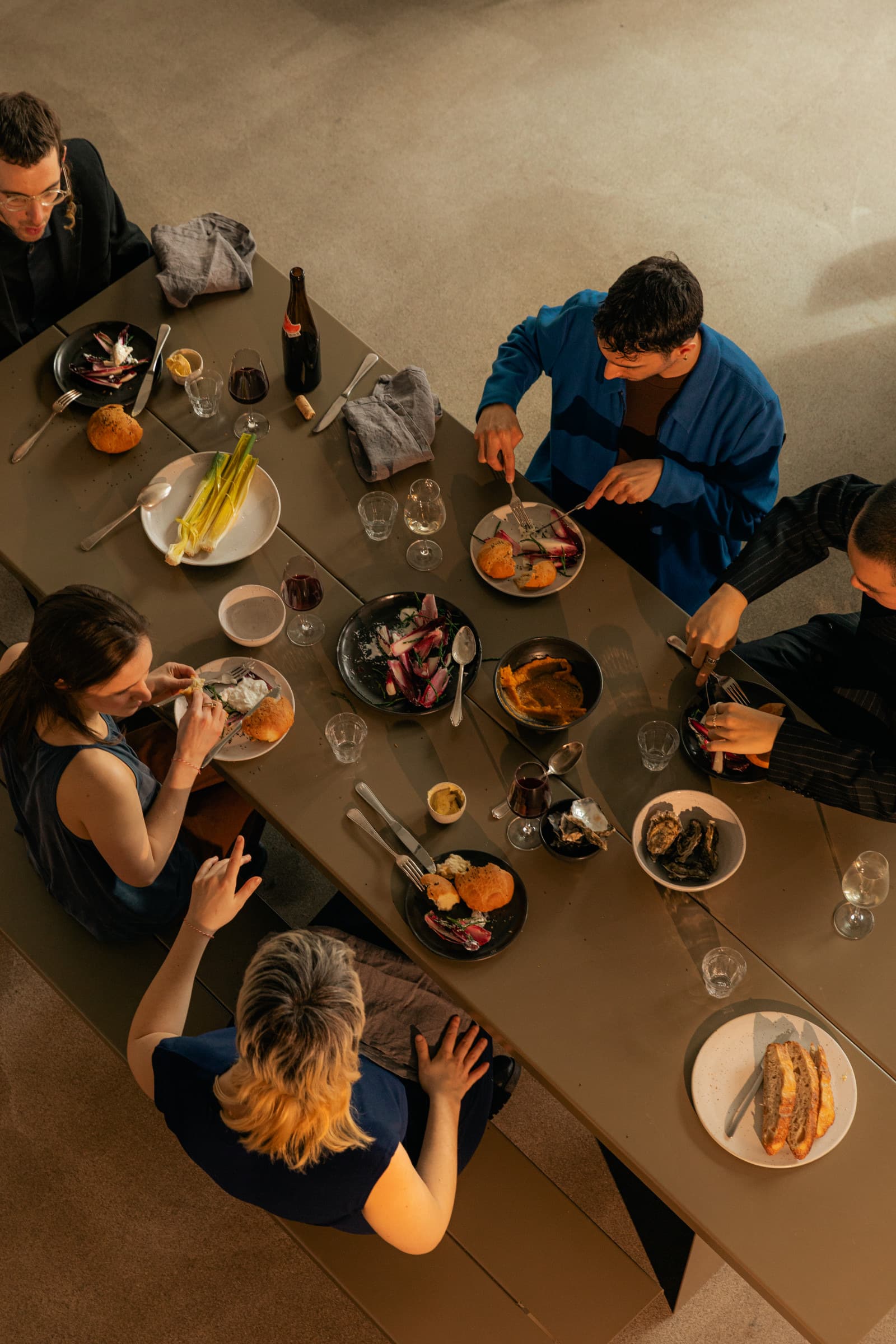 Een lange tafel van bovenaf met gasten die samen eten